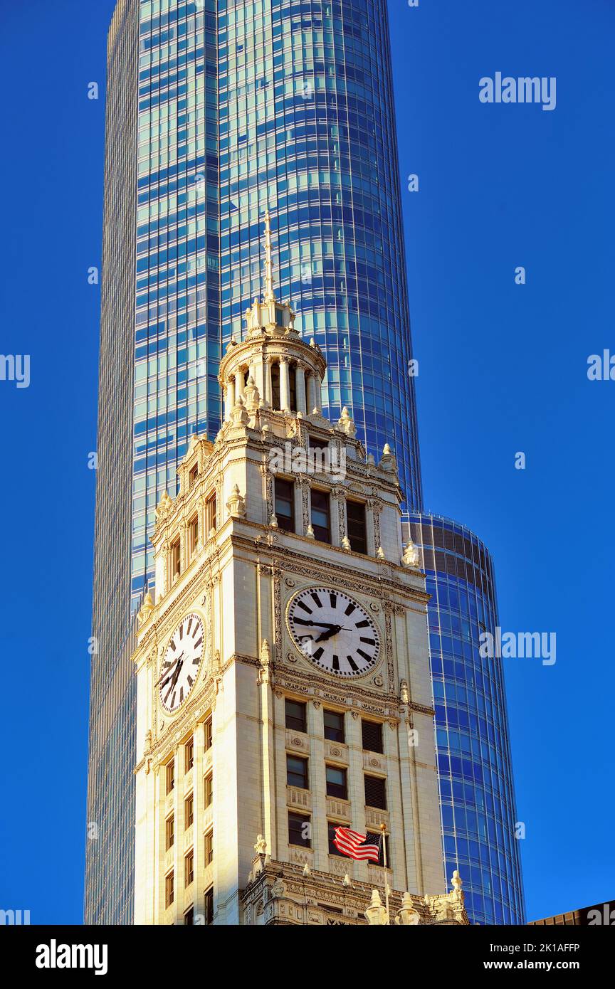 Chicago, Illinois, USA. Das Wrigley Building und die ausgestellten amerikanischen Flaggen stehen im Kontrast zum ultramodernen Trump Tower im Hintergrund. Stockfoto