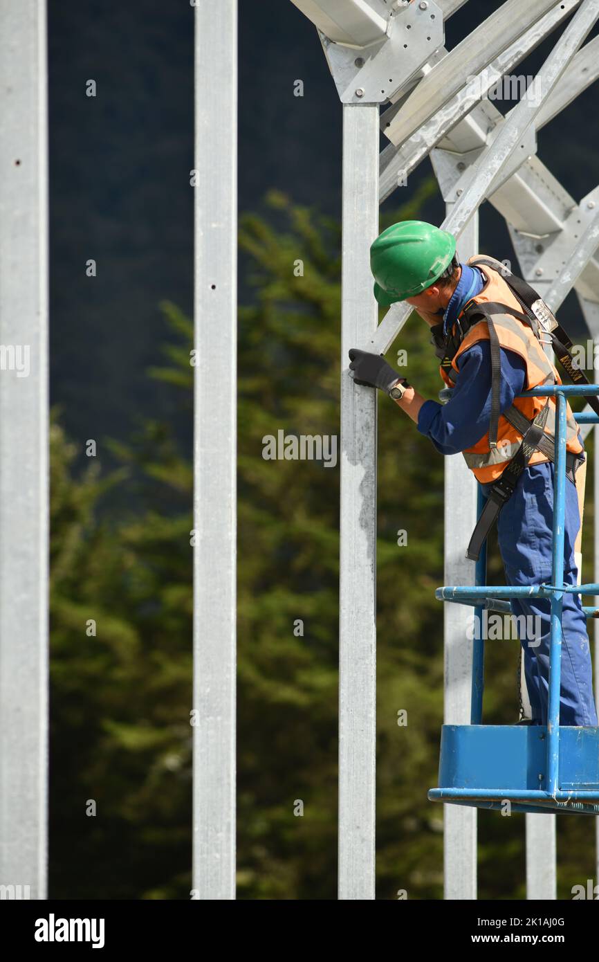 Ein Baumeister sichert sich die Rahmung in einem riesigen Tunnelhaus, das ein Herdenheim für Milchkühe in West Coast, Neuseeland, werden wird Stockfoto