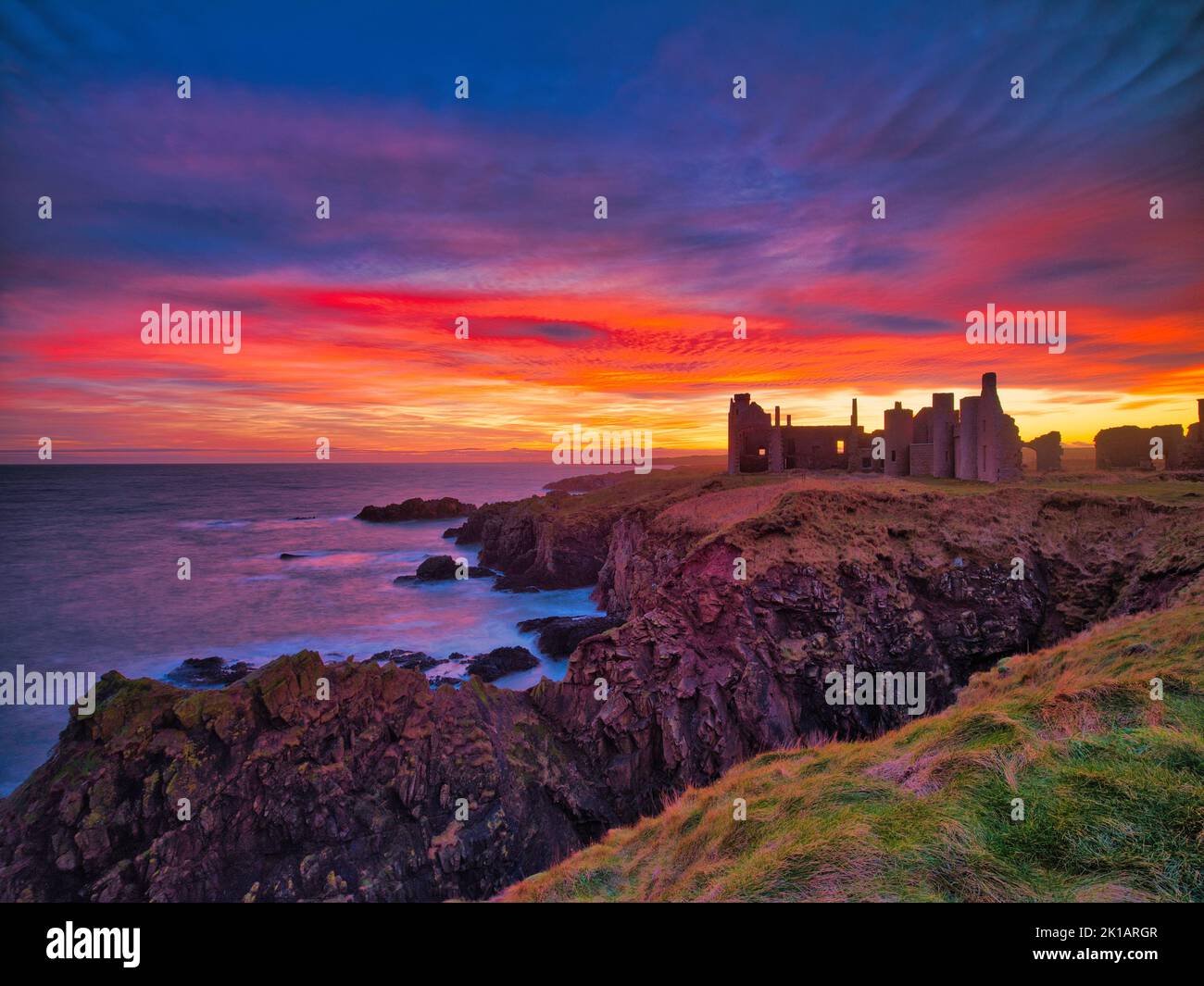 Slains Castle, Cruden Bay, Aberdeenshire, Schottland mit einem feurigen Sonnenuntergang. Stockfoto