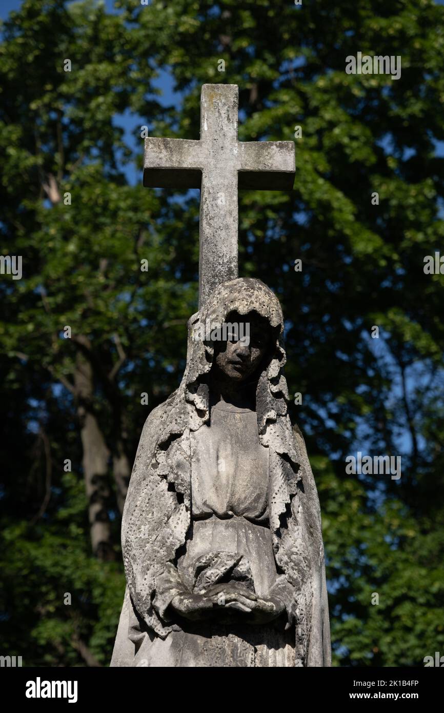 Heilige Maria mit Kreuz Friedhofskulptur, alte Statue in historischer Nekropole. Stockfoto