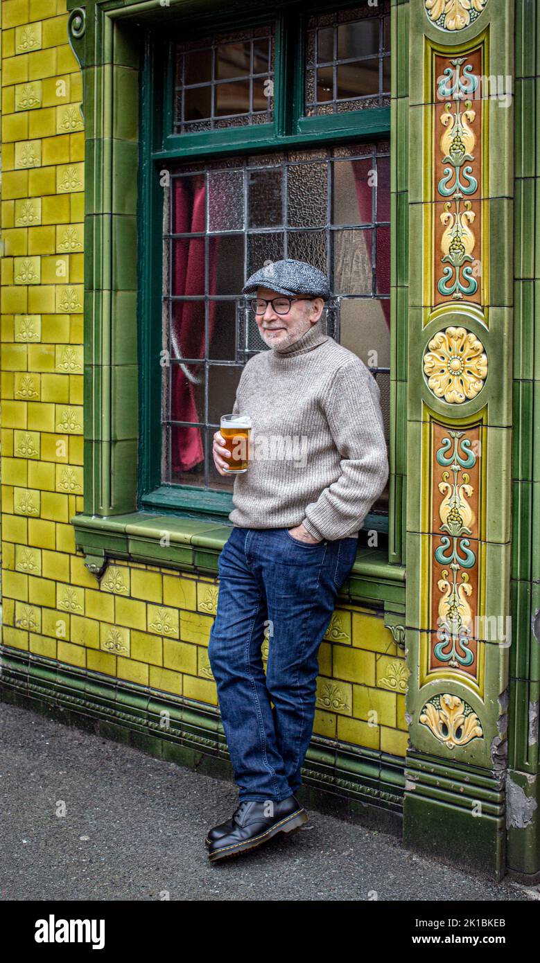 Mann steht vor einem Pub und genießt einen Drink im Peveril of the Peak , das sich in der Great Bridgewater Street in Manchester, England, befindet Stockfoto