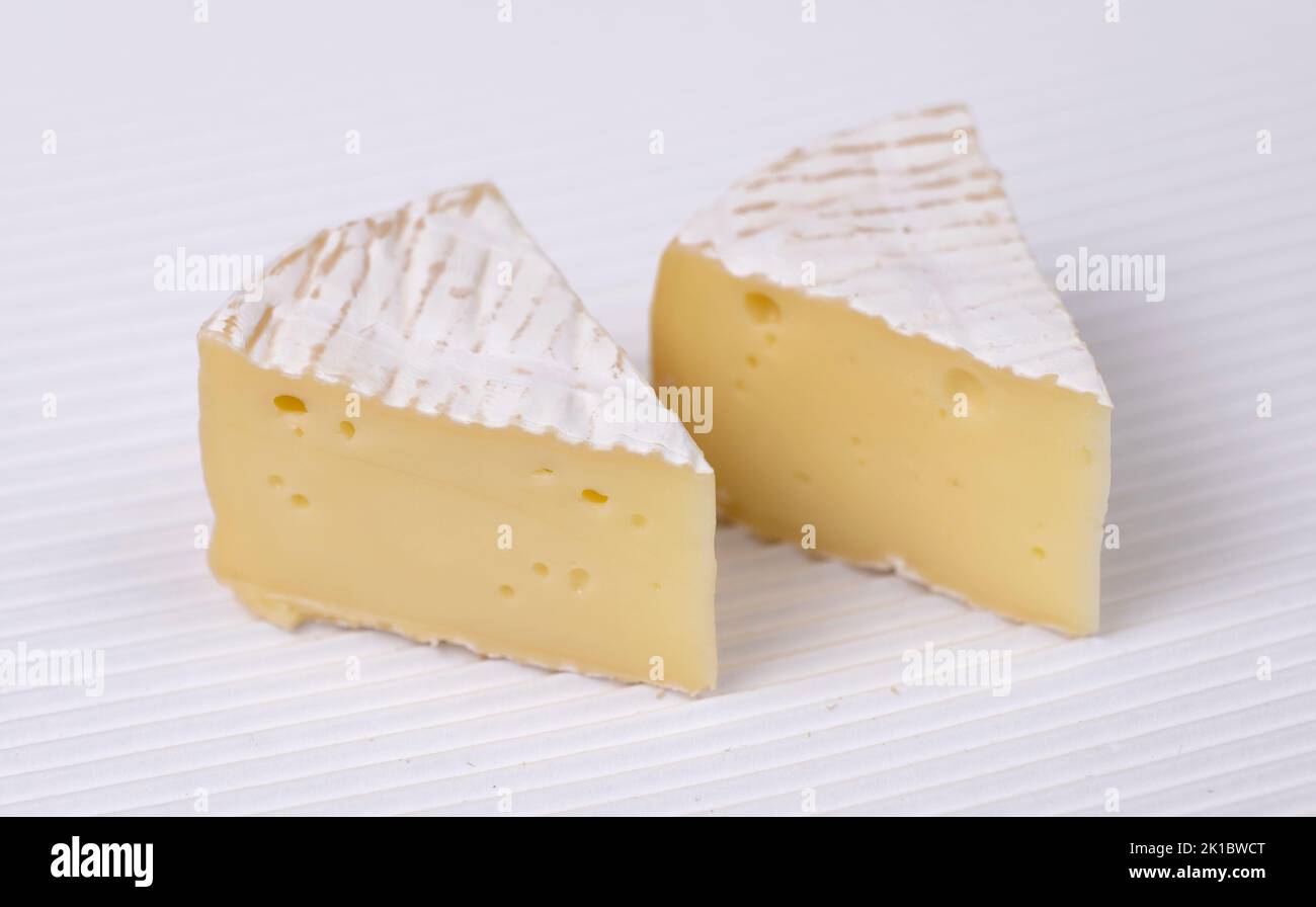Zwei Scheiben runder Brie-Käse auf weißem gewelltem Hintergrund, Nahaufnahme. Stockfoto