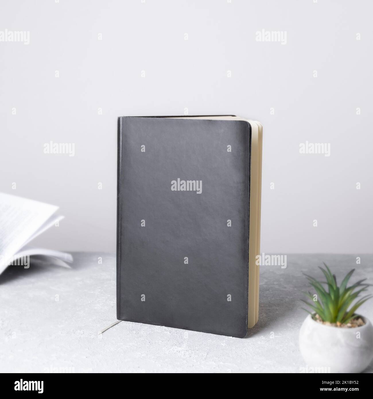 Schwarzes Buchmockup mit Arbeitsplatzzubehör. Vorderansicht. Platz für Text, Kopierraum, Mockup Stockfoto