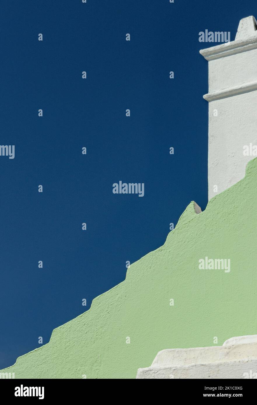 Bermuda Architektur Nahaufnahme Pastel Green House mit weißem Kamin und tiefblauem Himmel Stockfoto