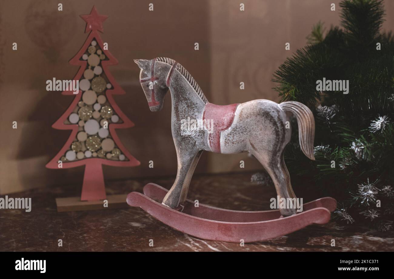 Weihnachtliche Komposition aus einem Holzpferd und einem Weihnachtsbaum im rustikalen Stil. Stockfoto