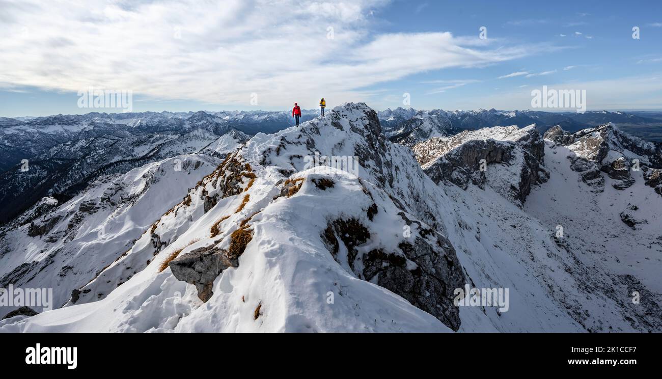 Zwei Bergsteiger auf einem schmalen felsigen, schneebedeckten Bergrücken, hinter Gipfelkrähen, Blick auf das Bergpanorama, Wanderung zur Ammergauer Hochplatte, im Herbst Ammergau Stockfoto