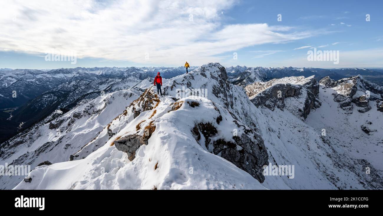 Zwei Bergsteiger auf einem schmalen felsigen, schneebedeckten Bergrücken, hinter Gipfelkrähen, Blick auf das Bergpanorama, Wanderung zur Ammergauer Hochplatte, im Herbst Ammergau Stockfoto