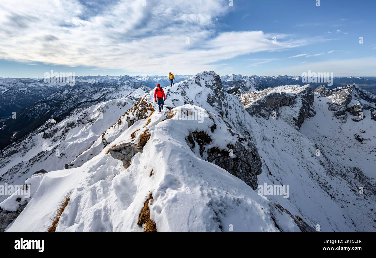 Zwei Bergsteiger auf einem schmalen felsigen, schneebedeckten Bergrücken, hinter Gipfelkrähen, Blick auf das Bergpanorama, Wanderung zur Ammergauer Hochplatte, im Herbst Ammergau Stockfoto
