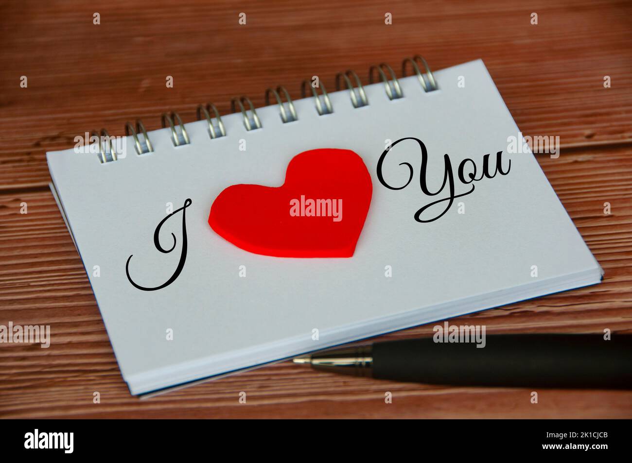 Ich liebe dich Text auf Notizblock mit Holzdeckel und Stift Hintergrund. Romantik und Beziehungskonzept. Stockfoto