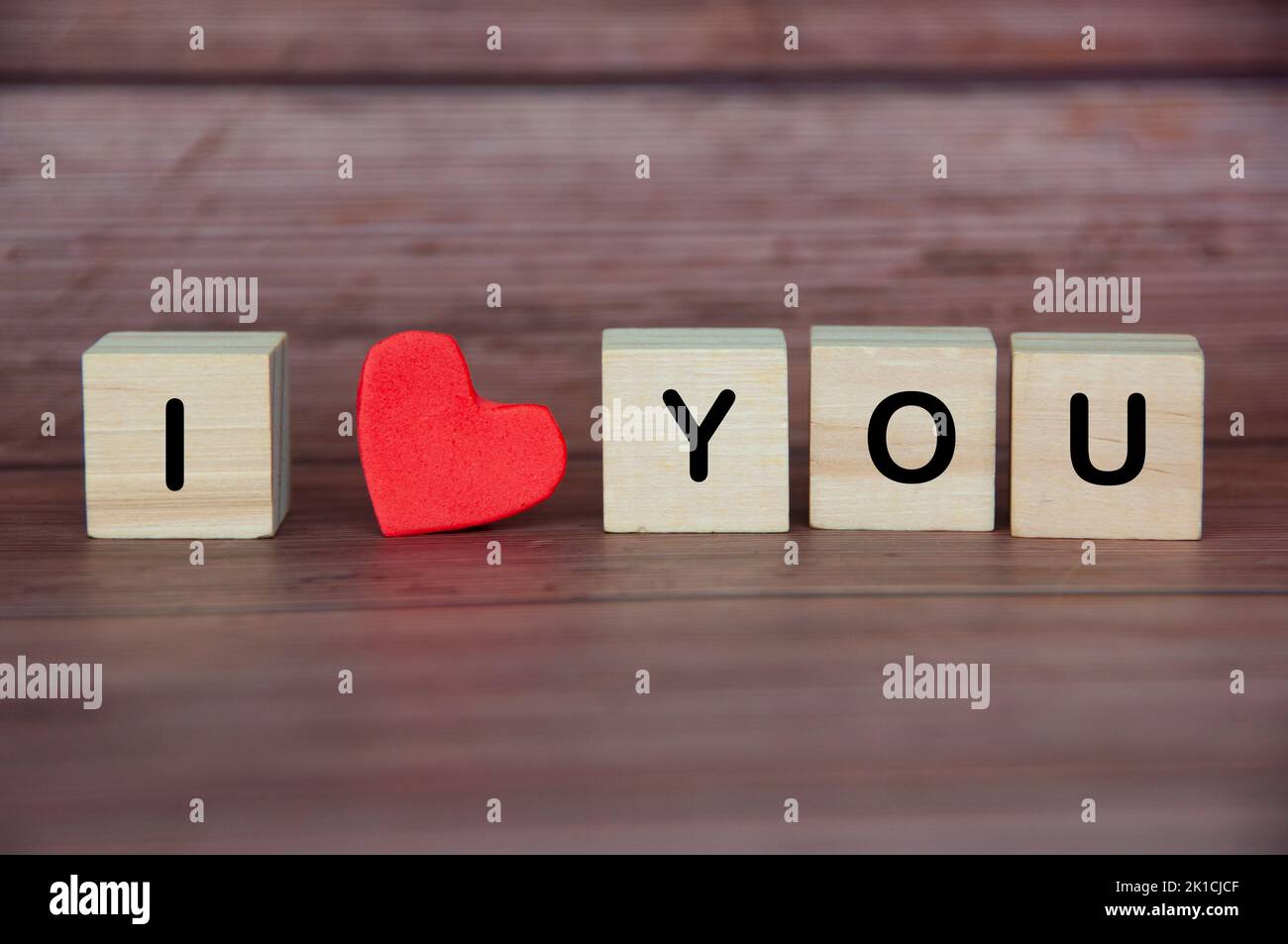 Ich liebe dich Text auf Holzblöcken mit Herzform und Holzhintergrund. Romantik und Beziehungskonzept. Stockfoto