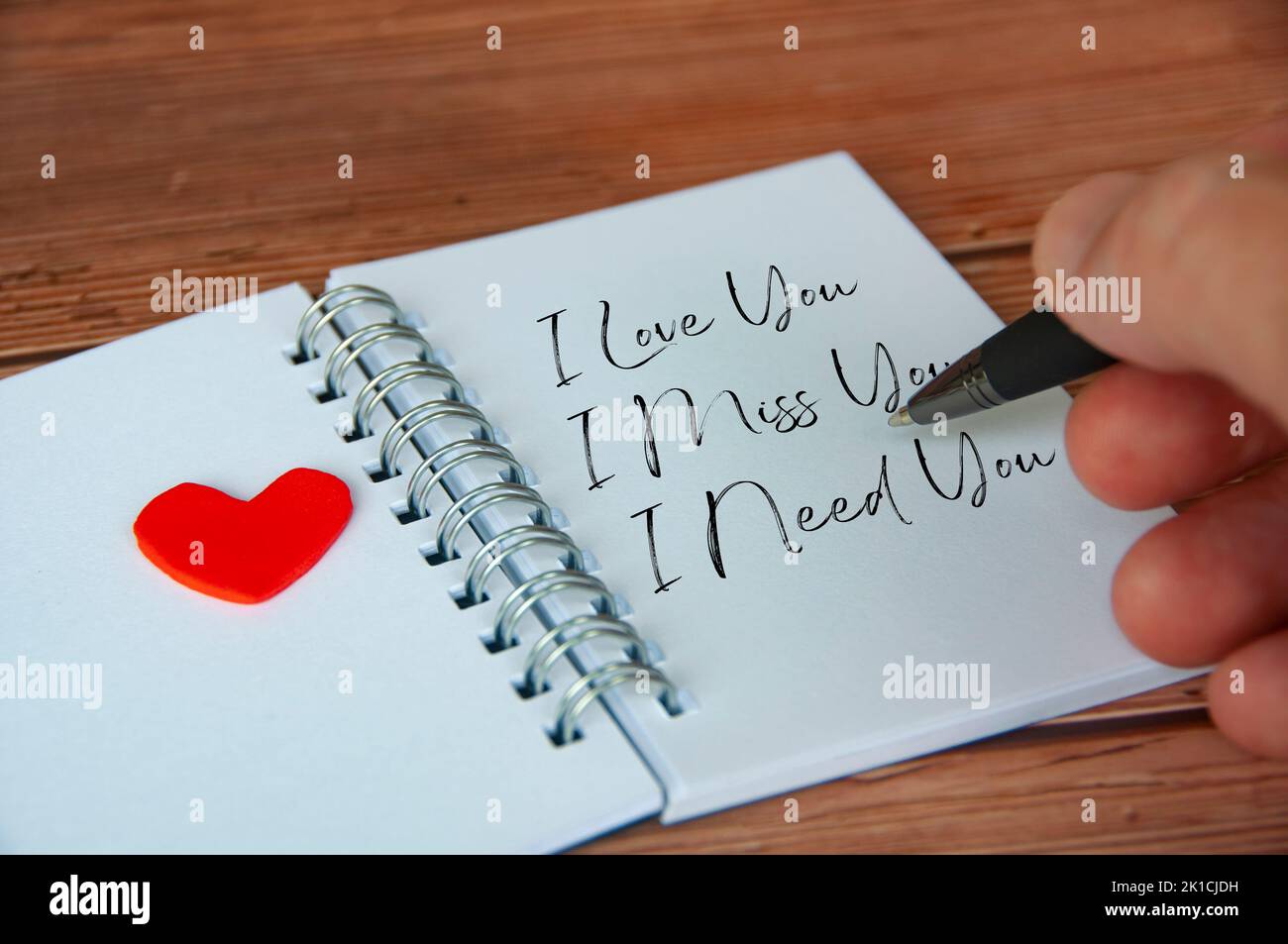 Ich liebe, vermisse und brauche Sie Text auf weißem Notizblock geschrieben. Romantik und Beziehungskonzept. Stockfoto