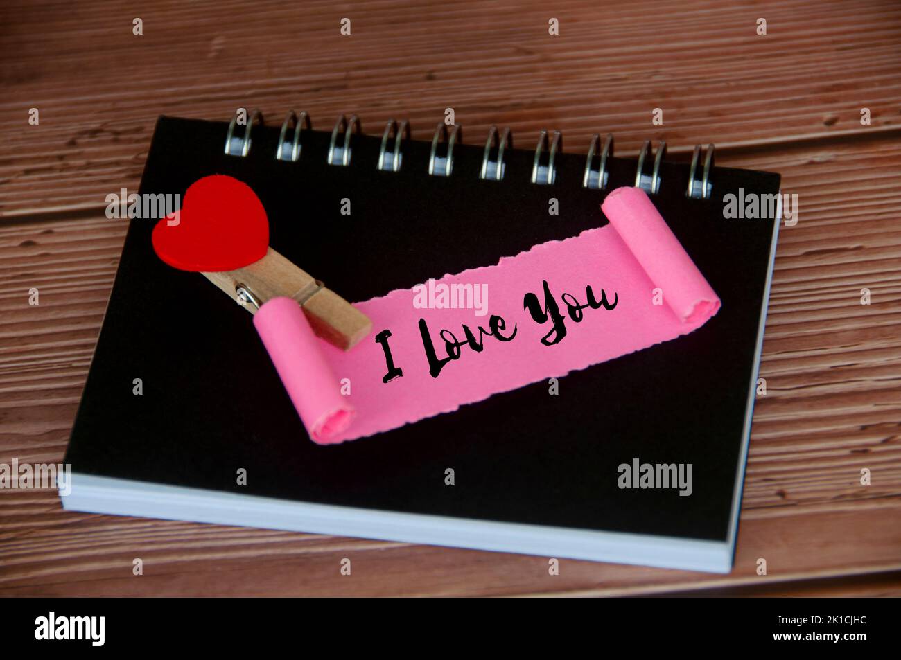 Ich liebe dich Text auf zerrissenem rosa Papier. Romantik und Beziehungskonzept. Stockfoto