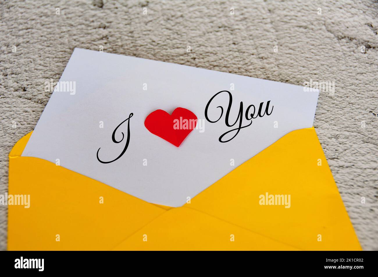 Ich liebe dich Text auf Notizblock in gelbem Umschlag. Romantik und Beziehungskonzept. Stockfoto