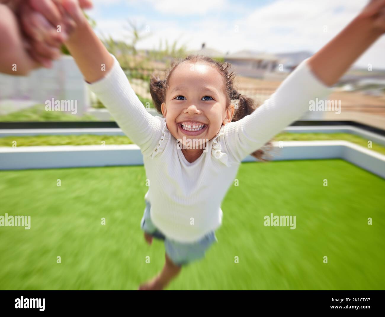 Mädchen Kind glücklich, Eltern pov Spaß im Garten und Eltern Hand schwingend Kind durch Arme in Kreisbewegung. Familienspiel auf grünem Gras Stockfoto