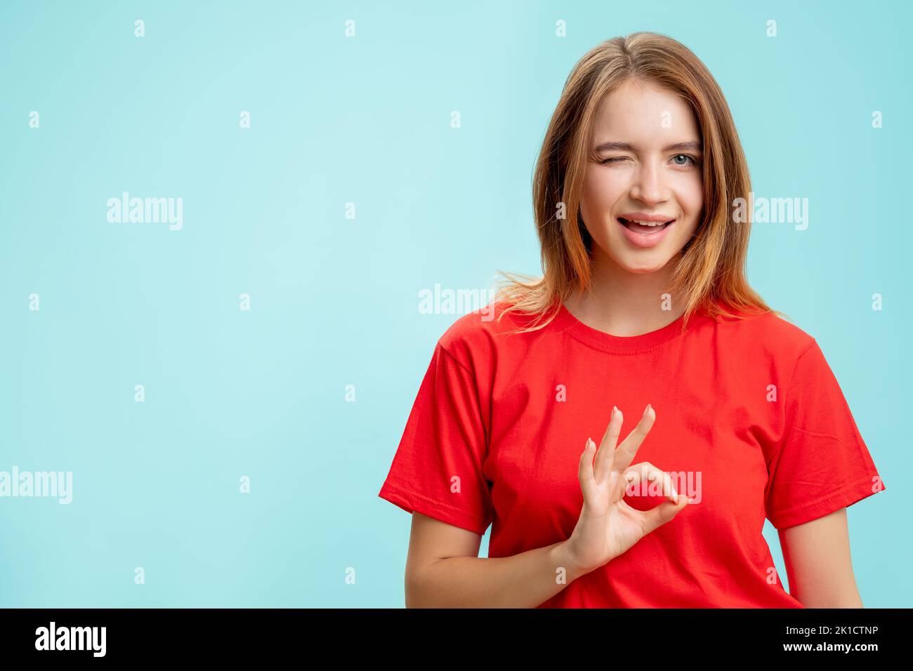 OK, Geste. Perfekte Wahl. Portrait einer enthusiastischen positiven Frau in rotem T-Shirt, die Angebot winking isoliert auf blauem Kopierraum kommerzieller Rückseite annimmt Stockfoto
