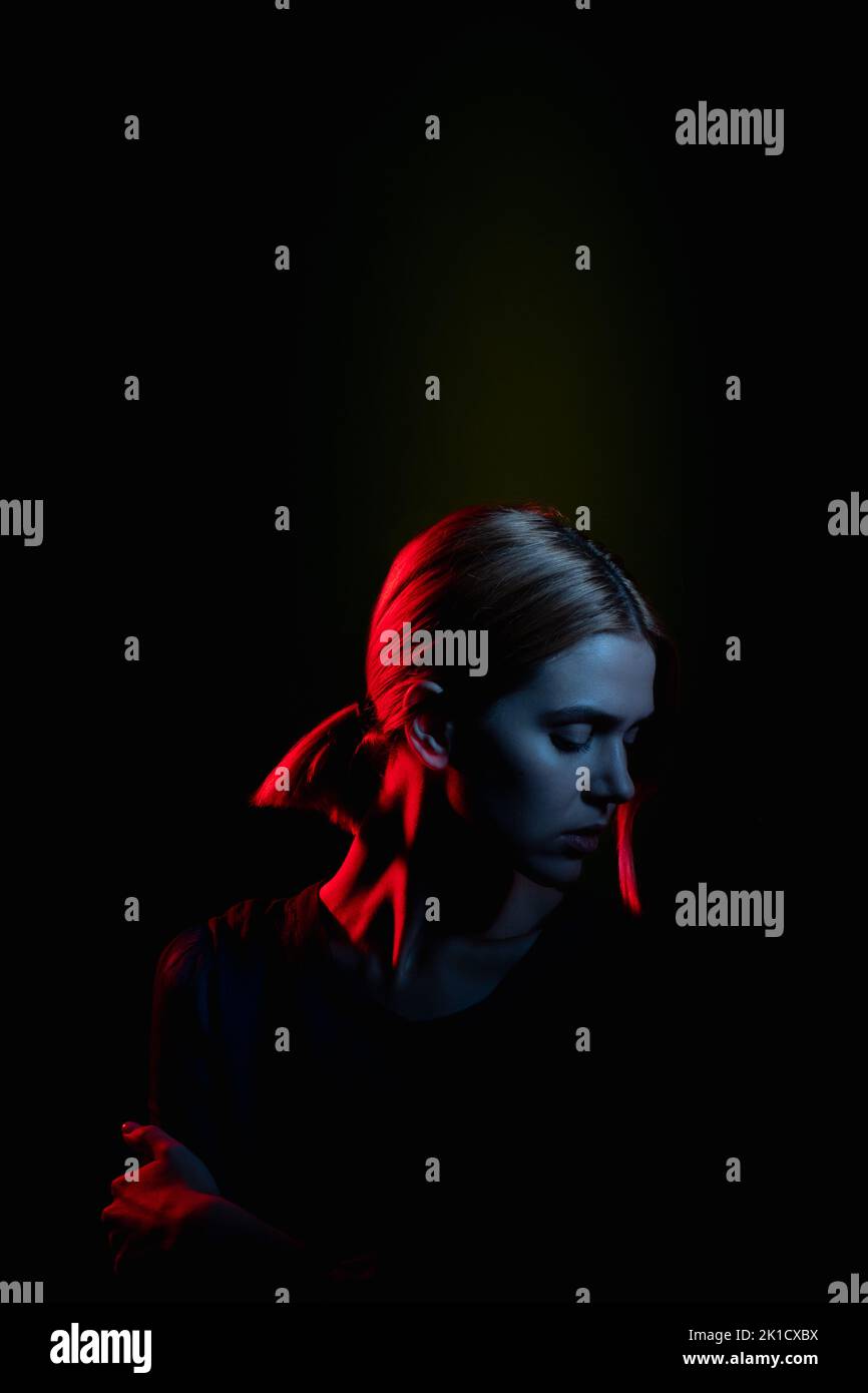 Weibliche Silhouette Porträt. Depressiv fühlen. Melandionisch Frau in Neonlicht leuchten isoliert auf schwarz. Psychologische Unterstützung. Häusliche Gewalt. Festgeklemmte PR Stockfoto