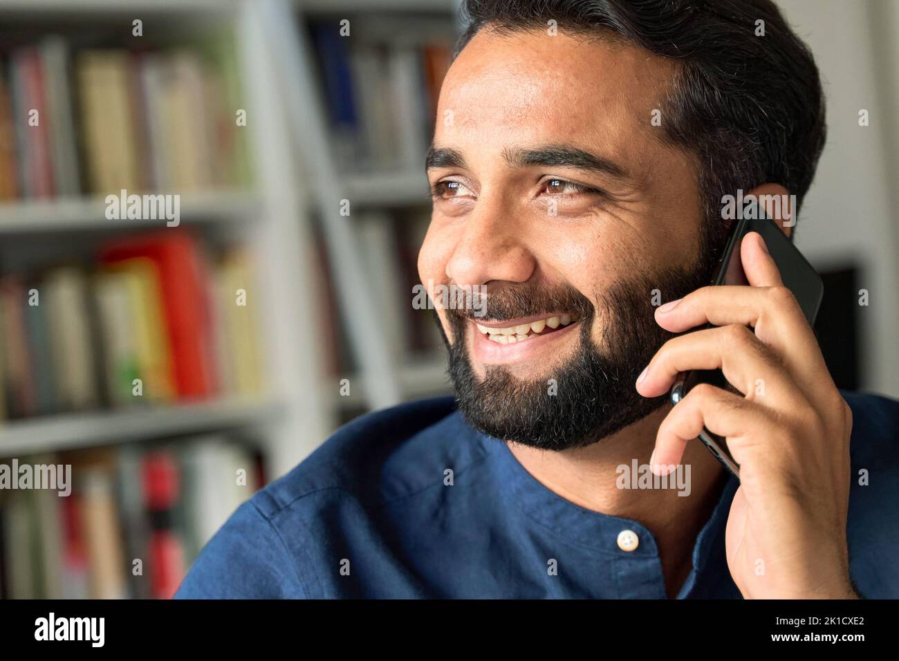 Lächelnder indischer Geschäftsmann, der am Telefon telefoniert und aus der Nähe telefoniert. Stockfoto