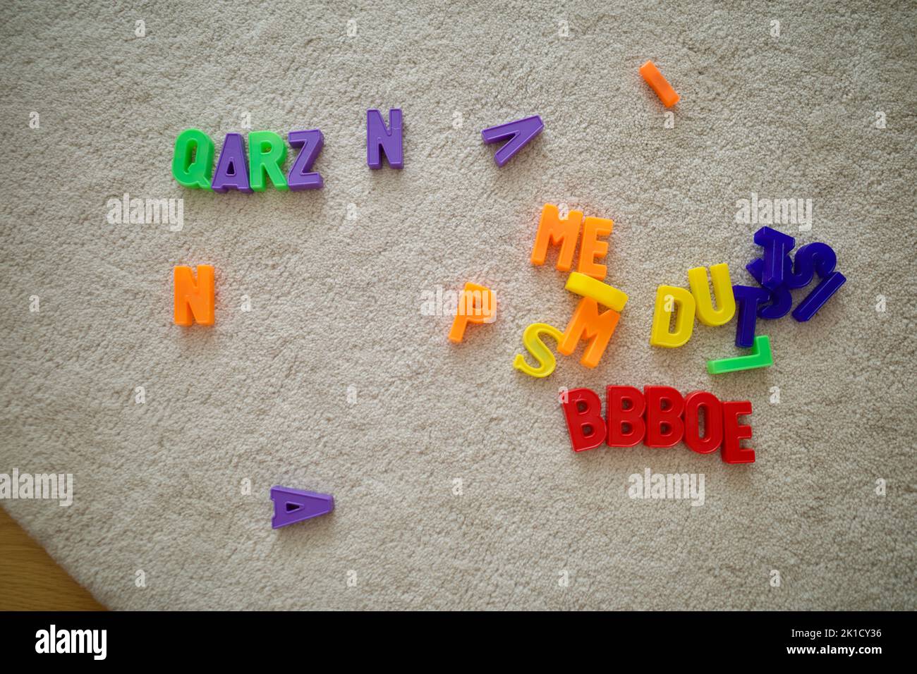 Magnet-Alphabet-Spielzeug zufällig auf einen weißen Teppich gelegt. Stockfoto