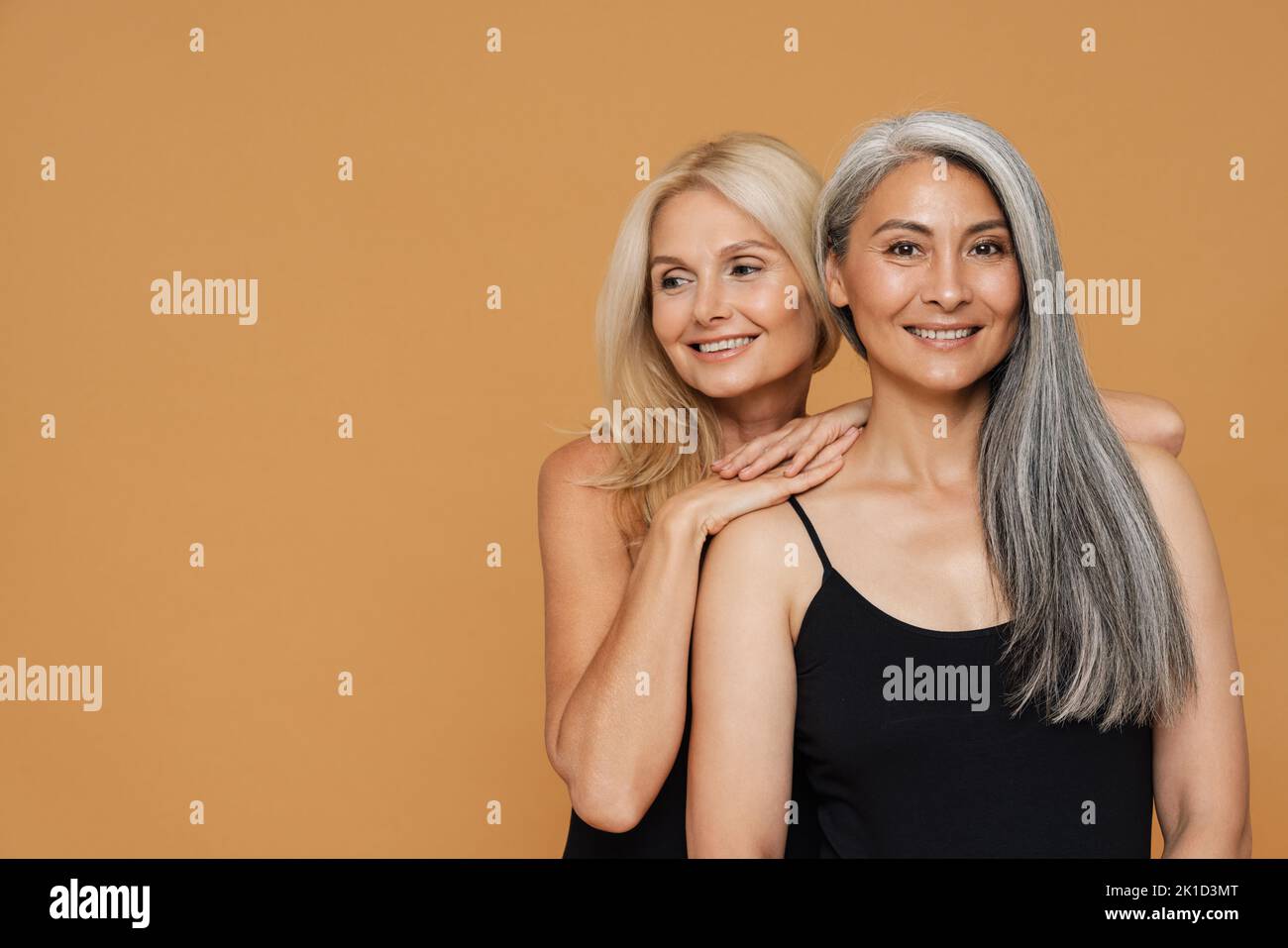 Reife multirassische schöne Frauen tragen Bodysuits lächelnd und posieren isoliert auf gelbem Hintergrund Stockfoto