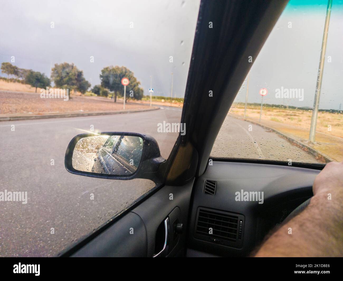 Bei regnerischem Wetter durch einen Kreisverkehr fahren. Reifengriffkonzept Stockfoto