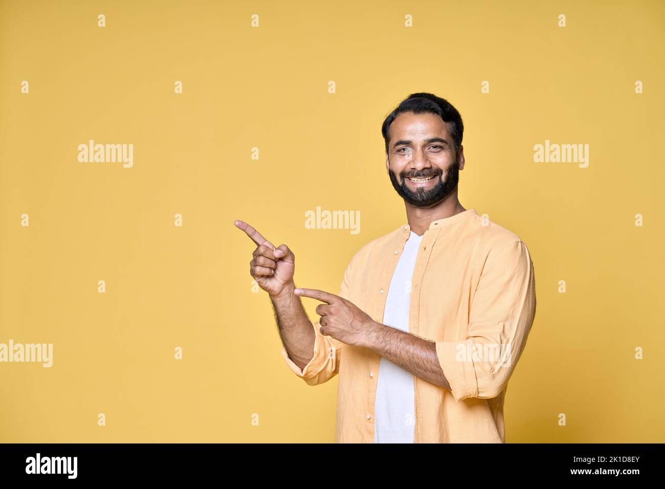 Glücklich indischen Mann zeigt Finger Werbung isoliert auf gelbem Hintergrund. Stockfoto