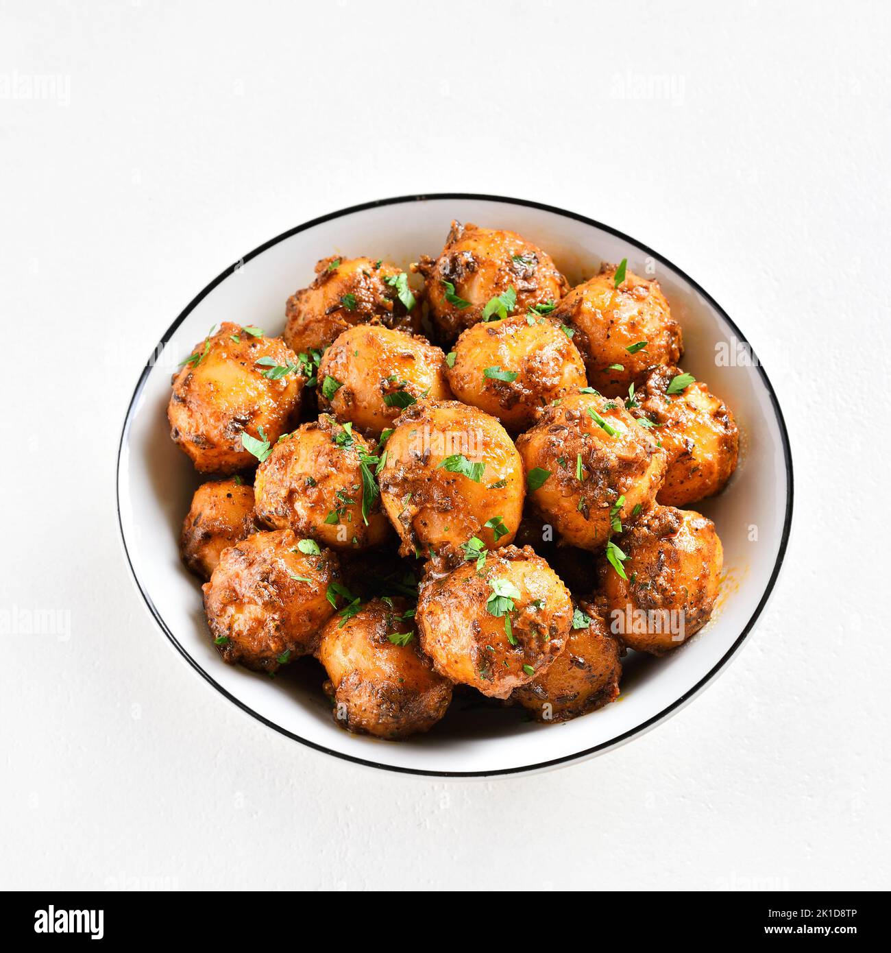 Bombay Potatoes. Gebratene kleine Kartoffeln mit Jeera-Samen und Koriander in einer Schüssel auf hellem Hintergrund. Beliebtes indisches Gericht. Stockfoto