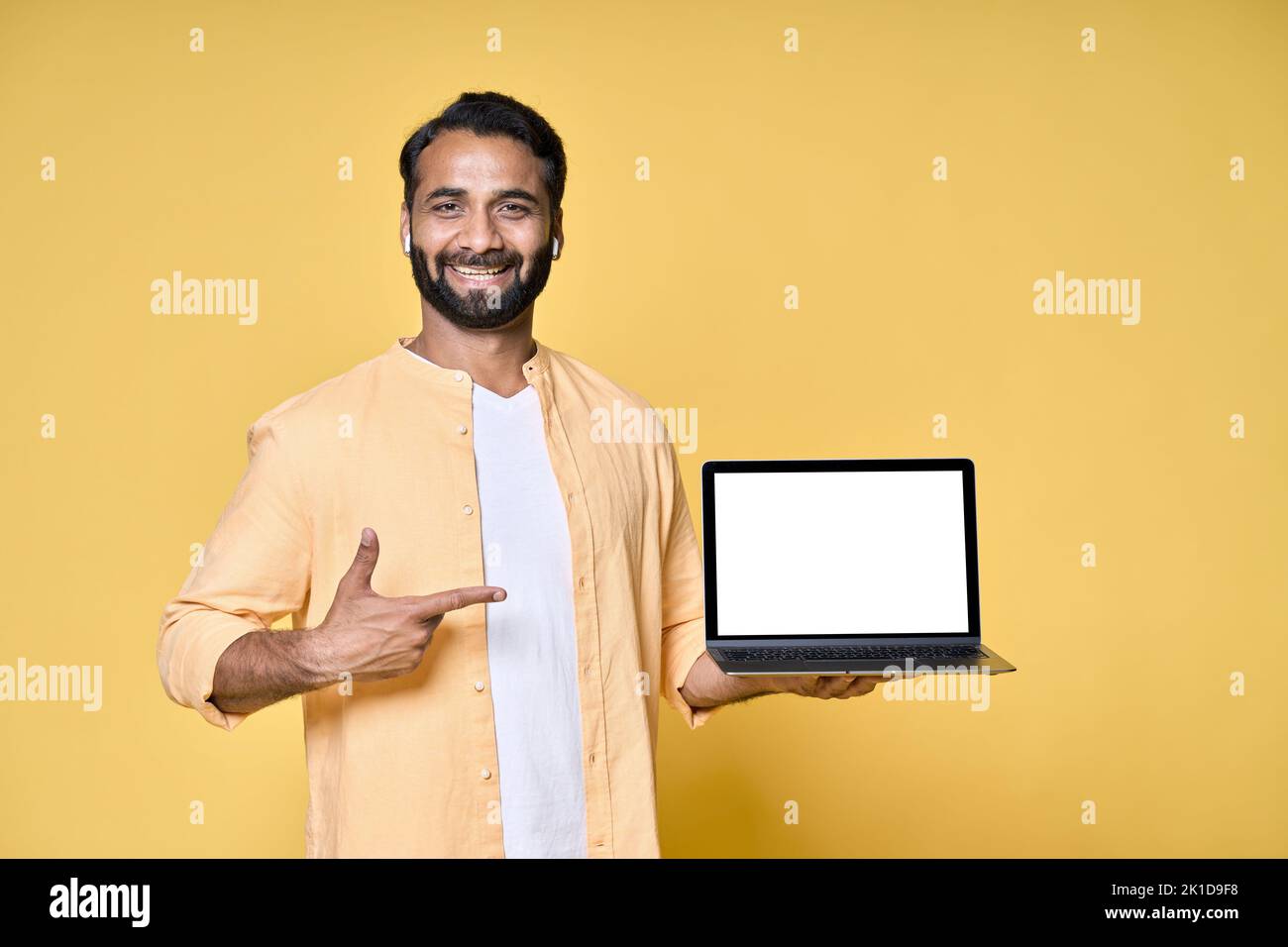 Glücklicher indischer Geschäftsmann Student zeigt auf Laptop-Modell isoliert auf gelb. Stockfoto
