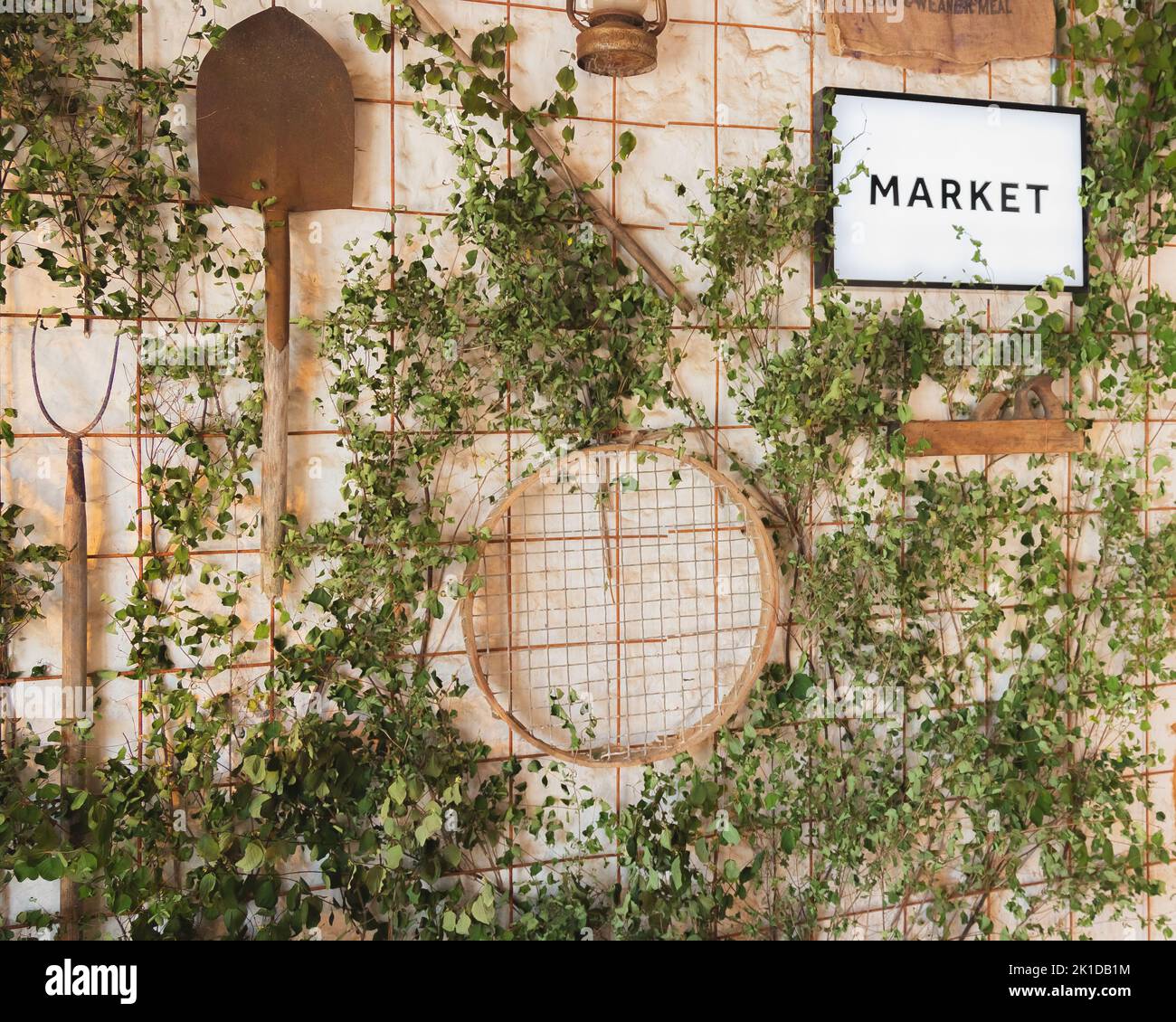 Marktschild auf einem dekorativen grünen und rustikalen Wanddisplay mit Gartengeräten und Schilder am Eingang des Bauernmarktes auf dem Land. Stockfoto