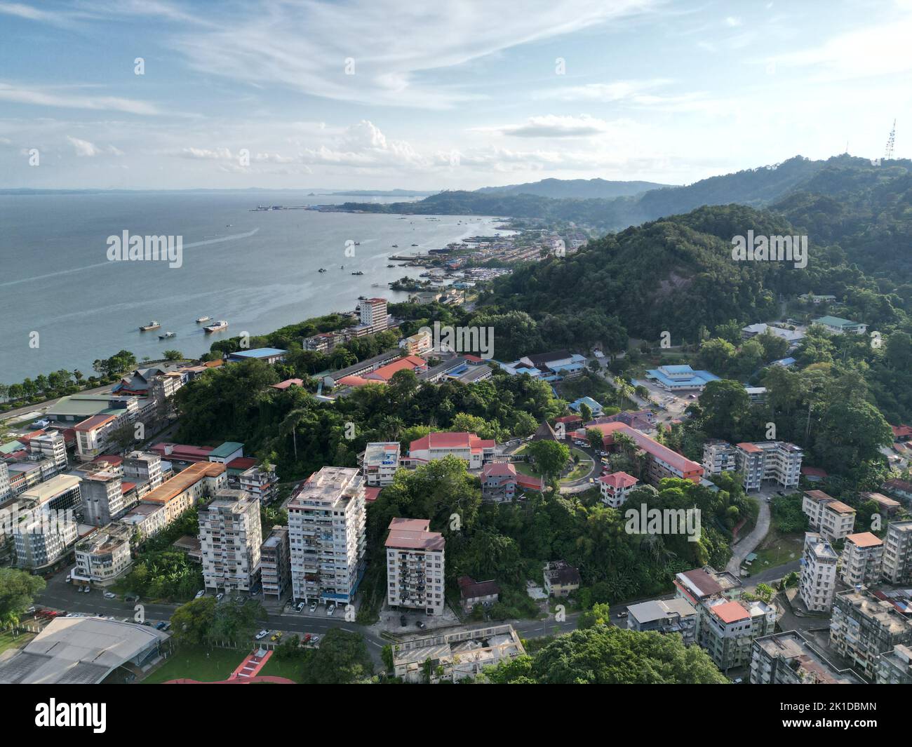 Eine Drohnenansicht von kleinen Häusern, Gebäuden und grünen Hügeln in der Nähe der Küste in Semporna, Malaysia Stockfoto