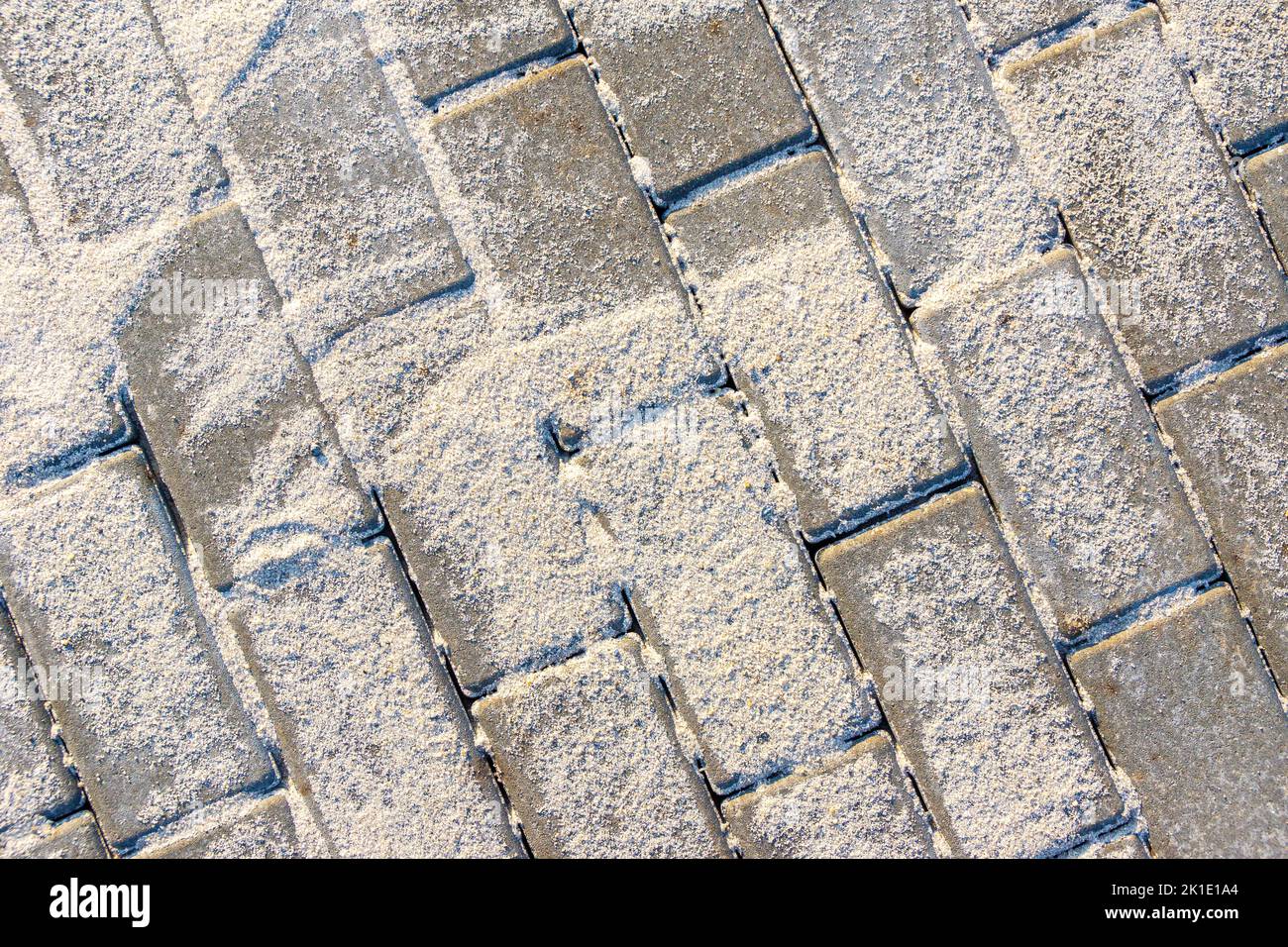 Verlegte Betonplatten sind mit leichtem Sand bedeckt, um die Fugen zu füllen, selektiver Fokus Stockfoto