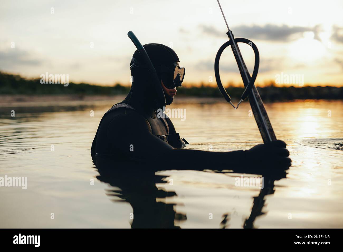 Speerfischen mit einer Speerpistole im Meer. Abenteuerlicher junger Mann mit Tauchausrüstung und Neoprenanzug mitten im Meer. Stockfoto