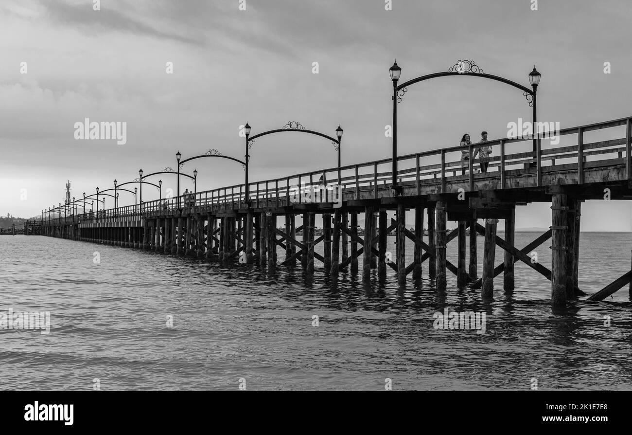 Hölzerner Pier bei White Rock, BC, Kanada, erstreckt sich diagonal in das Bild. Stadt White Rock Pier an bewölktem bewölktem Tag, BC, Kanada. Reisefoto, Kopie sp Stockfoto