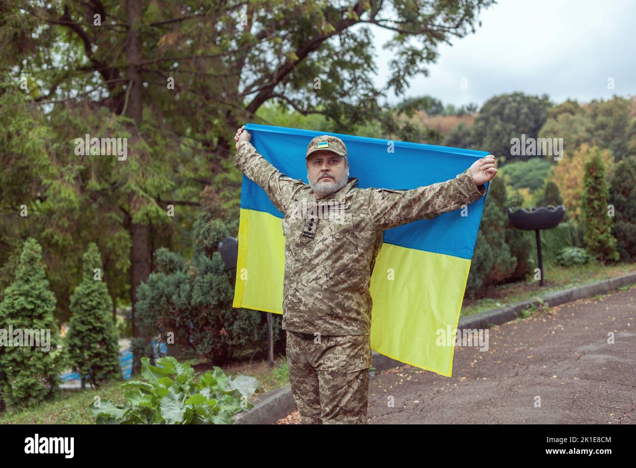 Der ukrainische Militärangehöriger hält die Flagge der Ukraine in seinen Händen. Krieg, Konflikt, Ukraine. Stockfoto