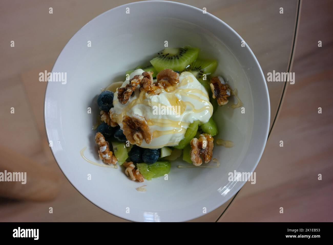 Das Frühstück mit Joghurt, Walnüssen und frischem Obst und Honig wurde überträufelt. Stockfoto