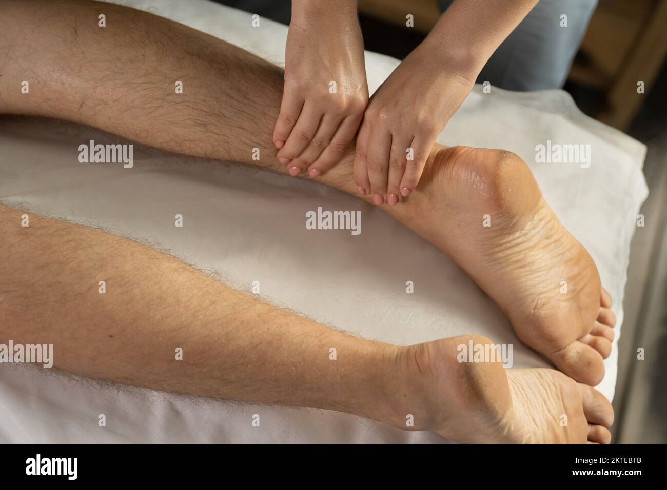 Nahaufnahme einer Therapeutin, die in der Klinik eine Bein- und Kälbermassage an den Sportpatienten auf dem Bett gibt, um ein Konzept für die Sport-Physiotherapie zu entwickeln Stockfoto