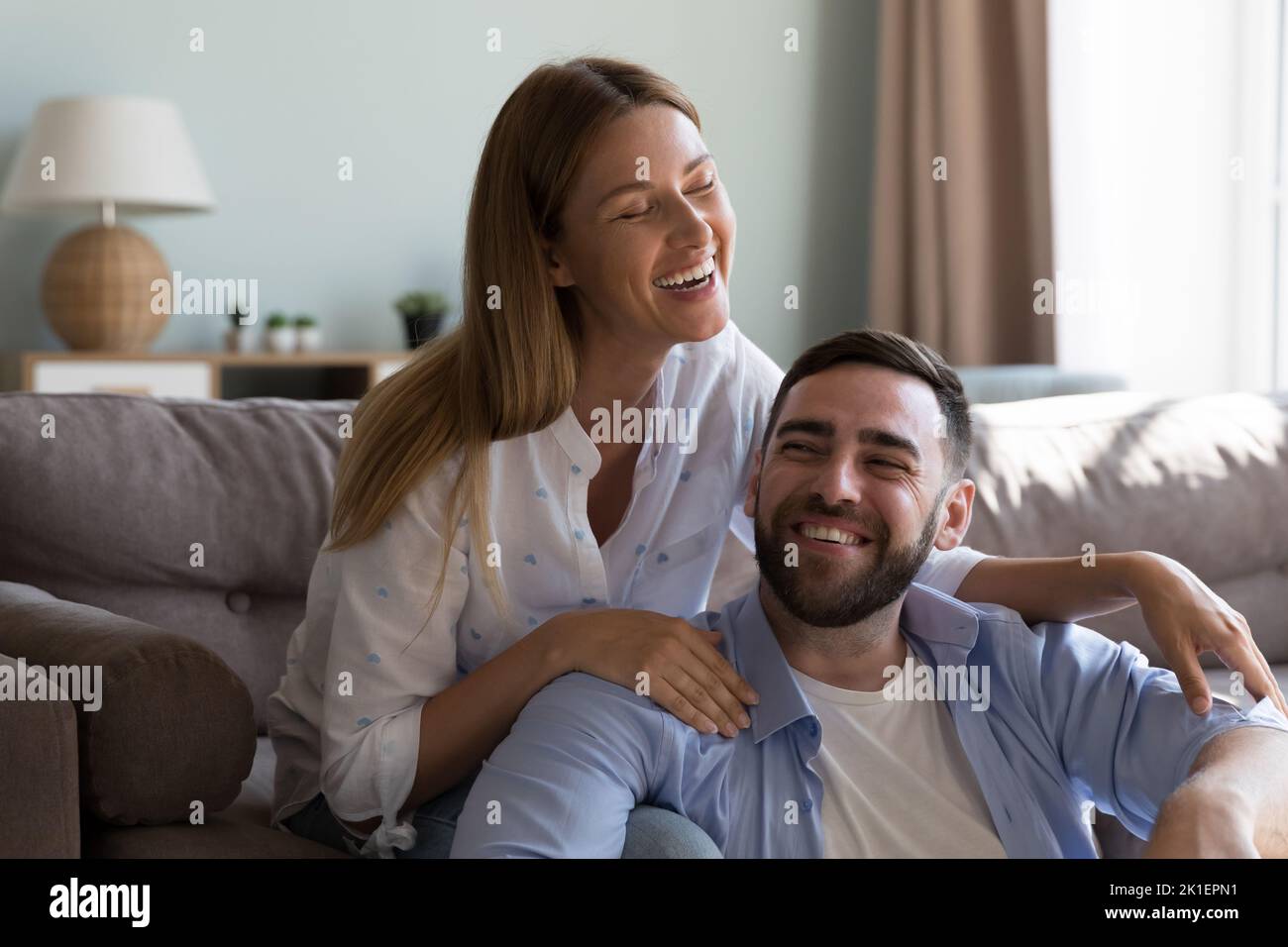 Fröhliches Ehepaar, das im Wohnzimmer redet und lacht Stockfoto
