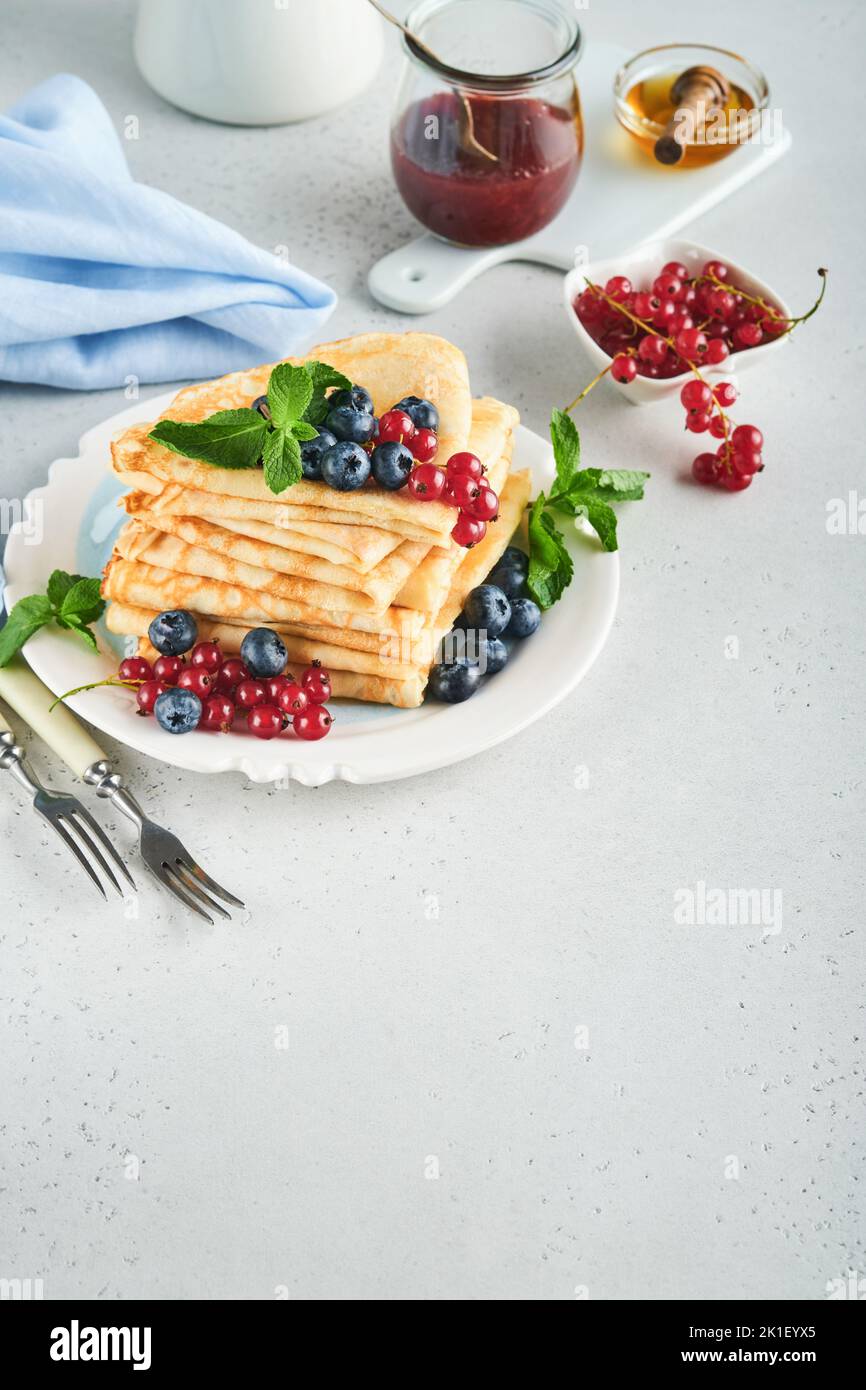 Pfannkuchen. Stapel von Crepes oder dünnen Pfannkuchen mit Beeren, Heidelbeeren, roten Johannisbeeren, Himbeeren und Honig zum Frühstück. Hausgemachtes Frühstück. Kopieren Sie den SPAC Stockfoto