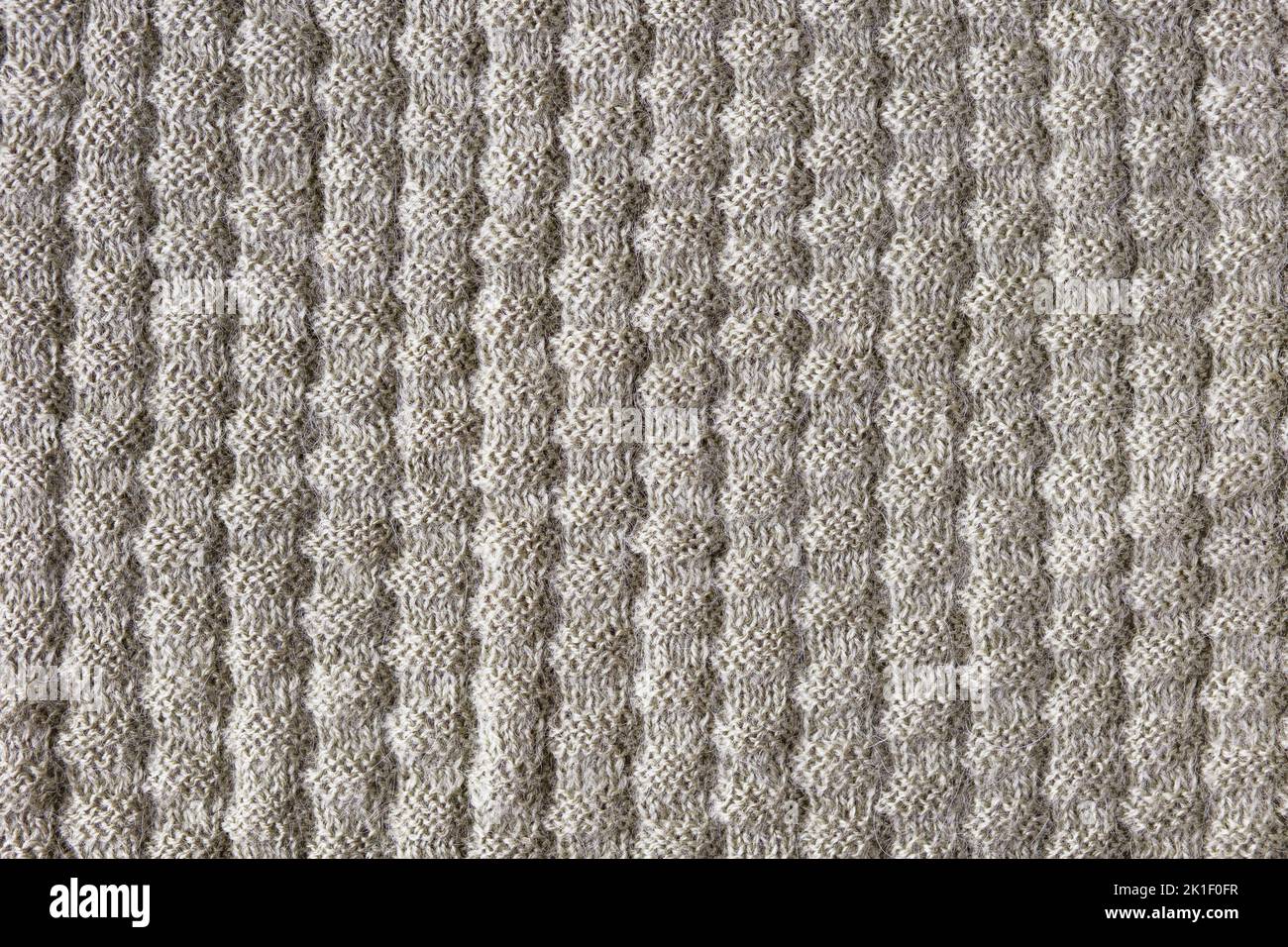 Gestrickter beiger Hintergrund. Große Strickware mit Muster. Nahaufnahme einer Strickdecke Stockfoto