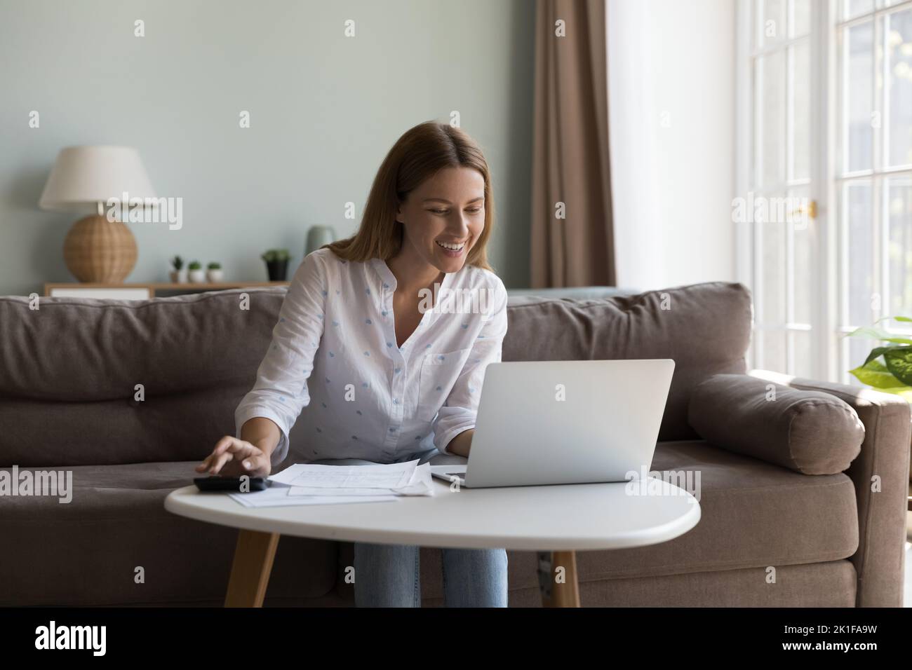 Glückliche fröhliche Millennial Frau mit Laptop und Rechner Stockfoto