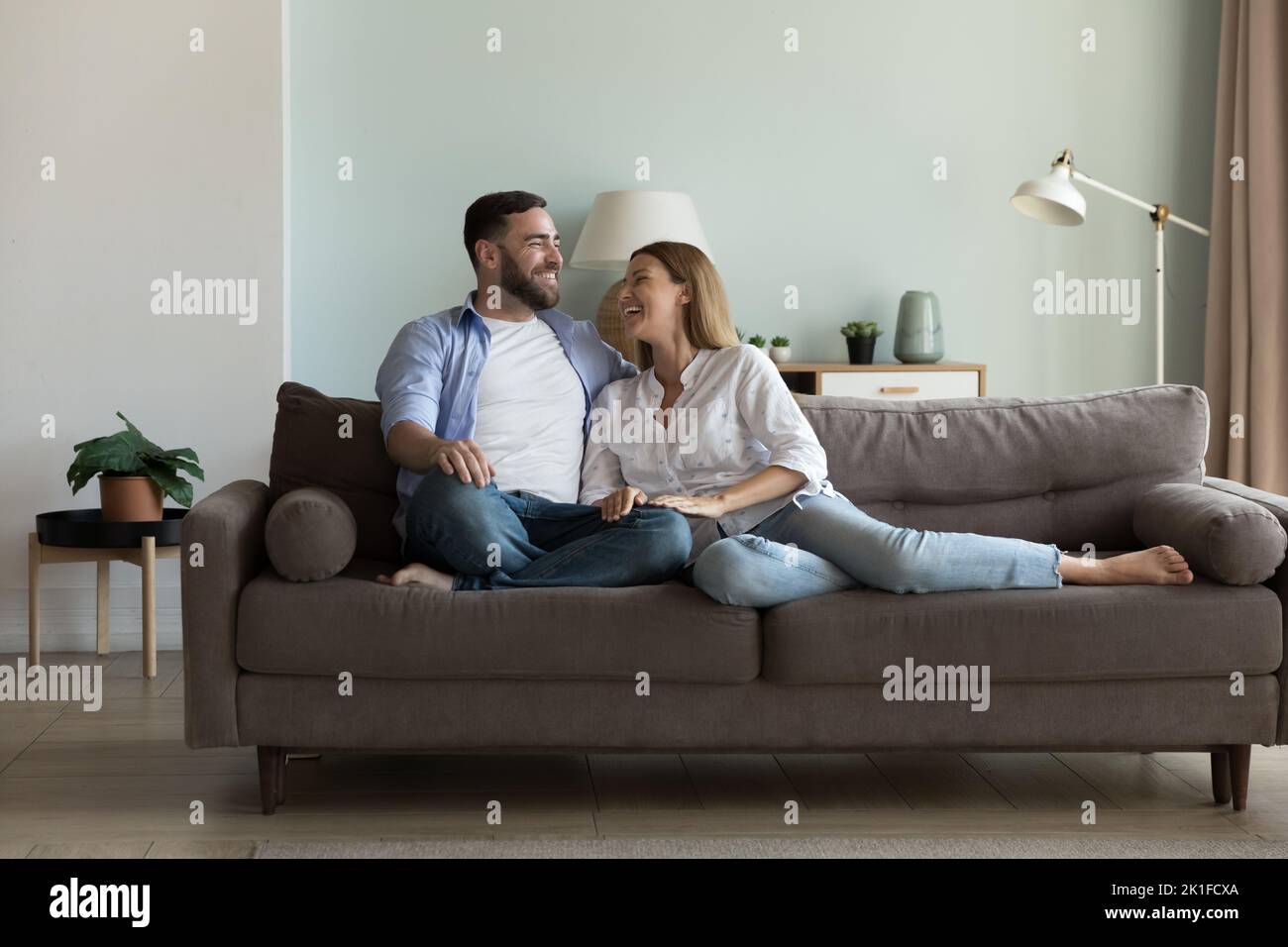 Glückliches fröhliches Ehepaar, das sich auf einer bequemen Couch ausruhte Stockfoto