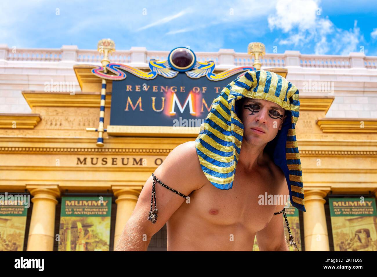 Ein männlicher Entertainer, der vor der Attraktion „Rache der Mumie“ auftrat. Das Gebäude hat ein Schild mit der Aufschrift Museum of Antiquities. Stockfoto