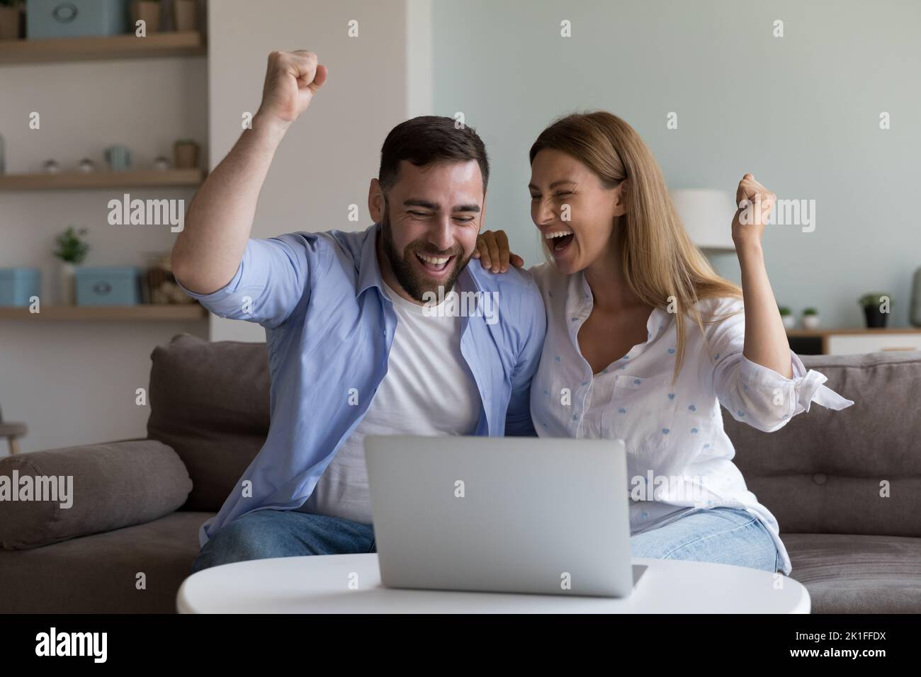 Fröhlich aufgeregt Millennial Ehemann und Ehefrau machen Sieger ja Hände Stockfoto