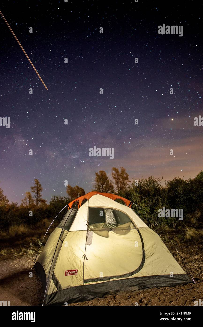 Nachtansicht eines kleinen Zeltes mit leuchtenden Sternen dahinter und einem Sternschnuppen in der Nähe von Prescott Valley, Arizona Stockfoto