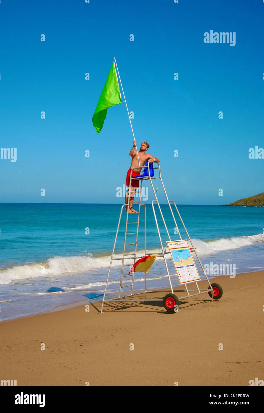 Ein Rettungsschwimmer, der die grüne Flagge in Plage de Surtainville, Normandie, Frankreich, Europa, hochhebt Stockfoto