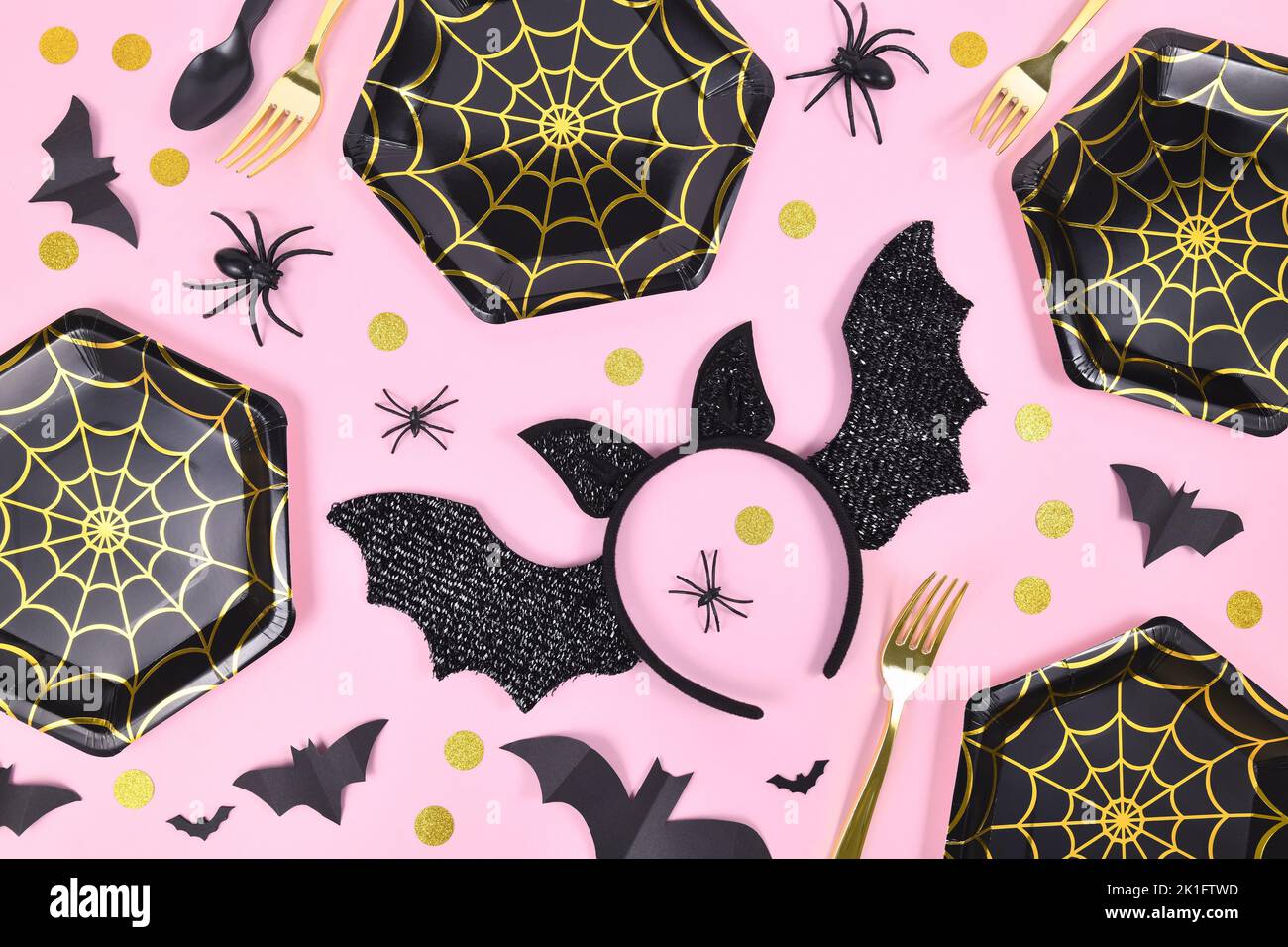 Halloween Party flach legen mit schwarzen und goldenen Spinnennetz Platten, Spinnen und Konfetti auf rosa Hintergrund Stockfoto