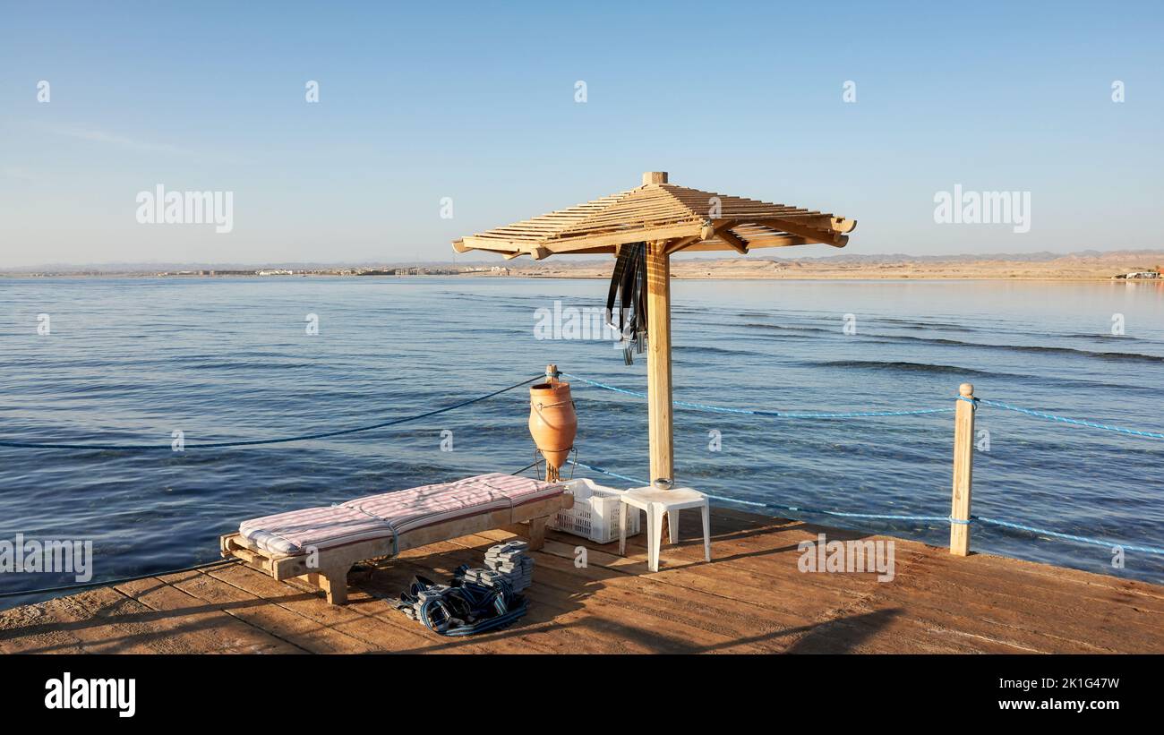 Sonnenschirm aus Holz, Sonnenliege und Tauchgewichte auf einer Pier-Plattform, Marsa Alam, Ägypten. Stockfoto