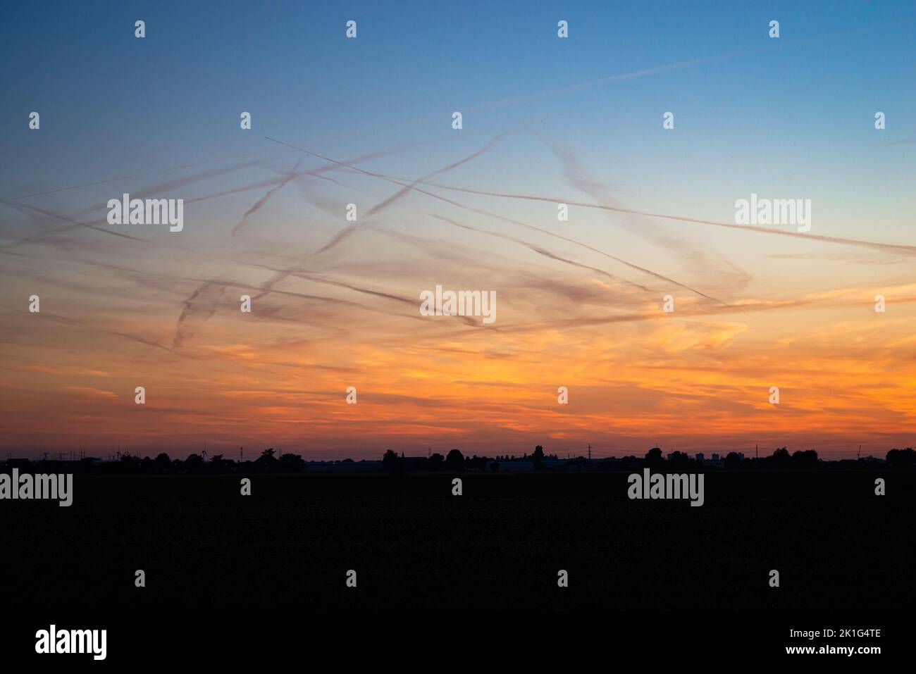 Viele Kondensstreifen am Abendhimmel, die durch die Emission von Wasserdampf aus Flugzeugen in großer Höhe gebildet werden Stockfoto
