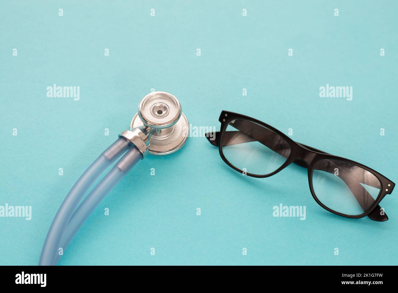 Medizinisches blu Stethoskop und schwarze Brillen auf blu-Hintergrund. Einfach minimalistisches Design mit Medizingeräten Doctor Stethoskop und klassischer Brille Stockfoto