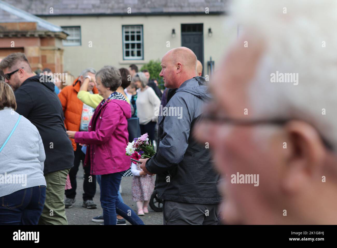 Ein Mann legt Blumen in Hillsborough Castle Gates, Royal Hillsborough, Nordirland Stockfoto