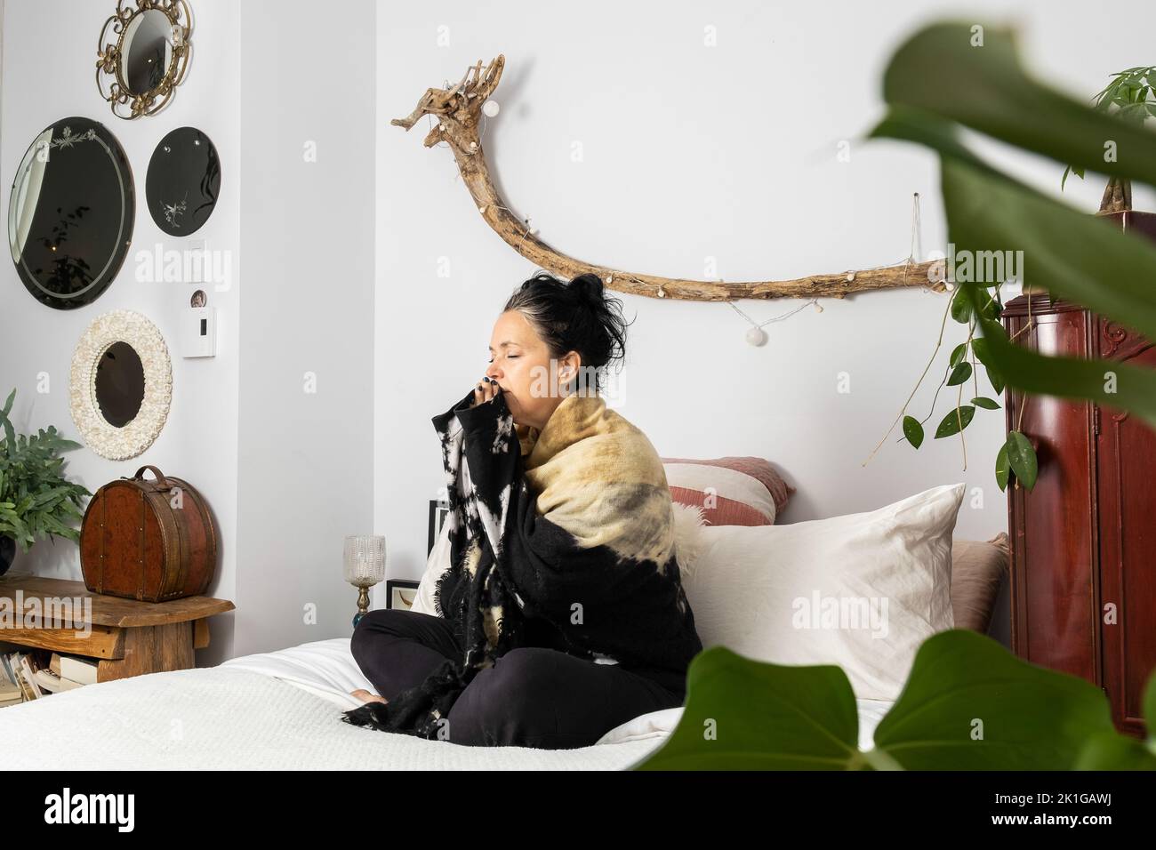 Eine Frau mittleren Alters meditierte auf ihrem Bett sitzend, verloren in ihren Gedanken. Hochwertige Fotos Stockfoto